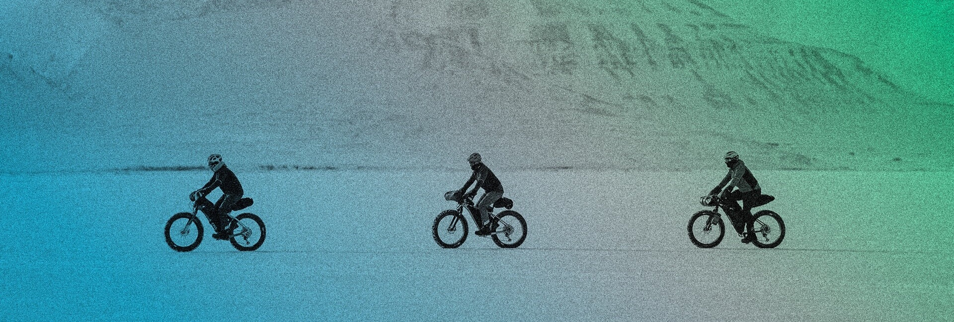 Three cyclists bike across a wintery tundra. A green to blue gradient is layered on the image.