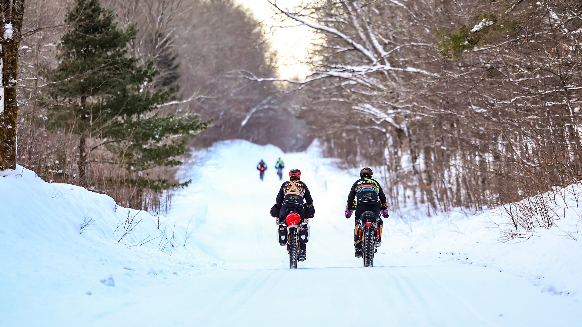 Fat bikers riding snowy road in winter on fully loaded fat bikes