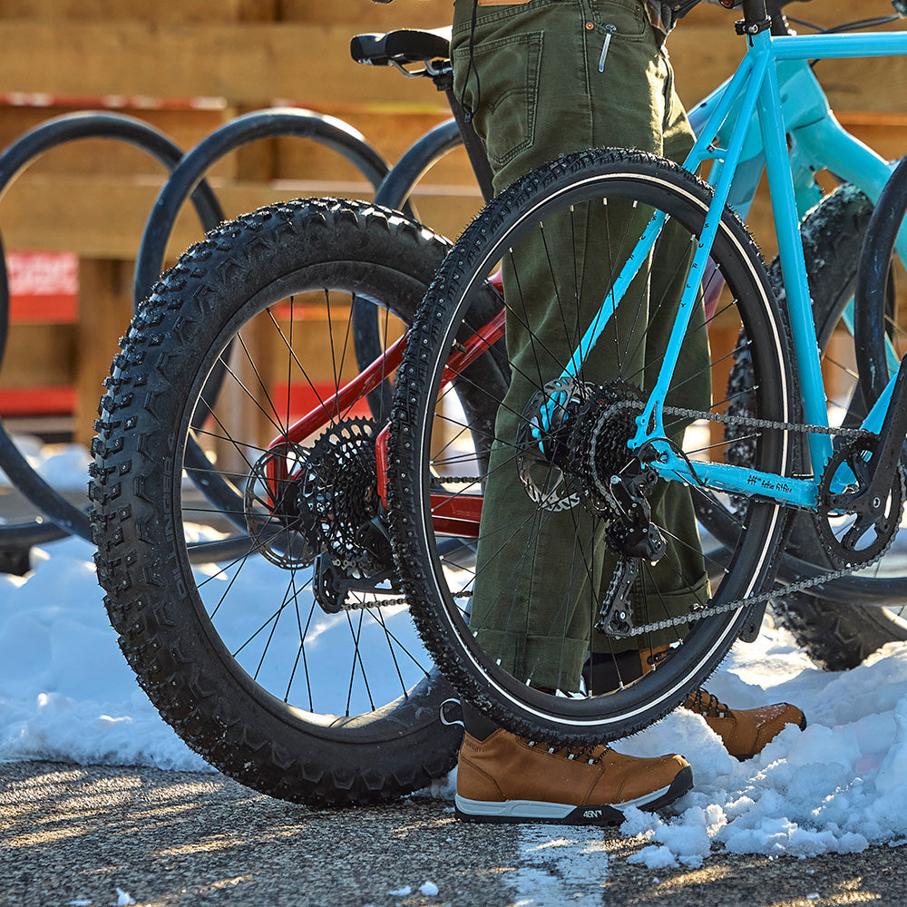 Cyclist parking bike with studded tires  at snowy outdoor bike rack