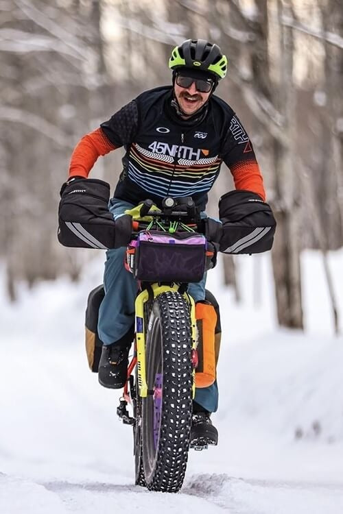 Brian Geshel riding fat bike on snowy road bike loaded with gear for bike packing