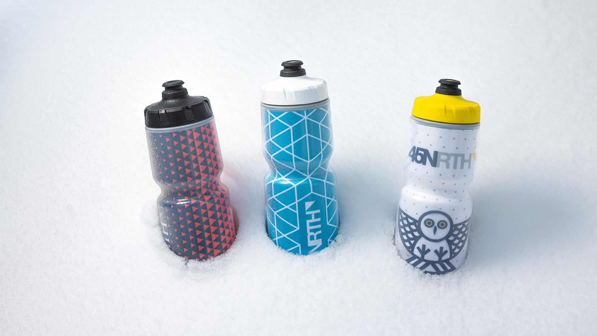 Three 45NRTH water bottles side by side in snow